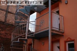 Außentreppe an orangefarbenem Haus mit Balkon.