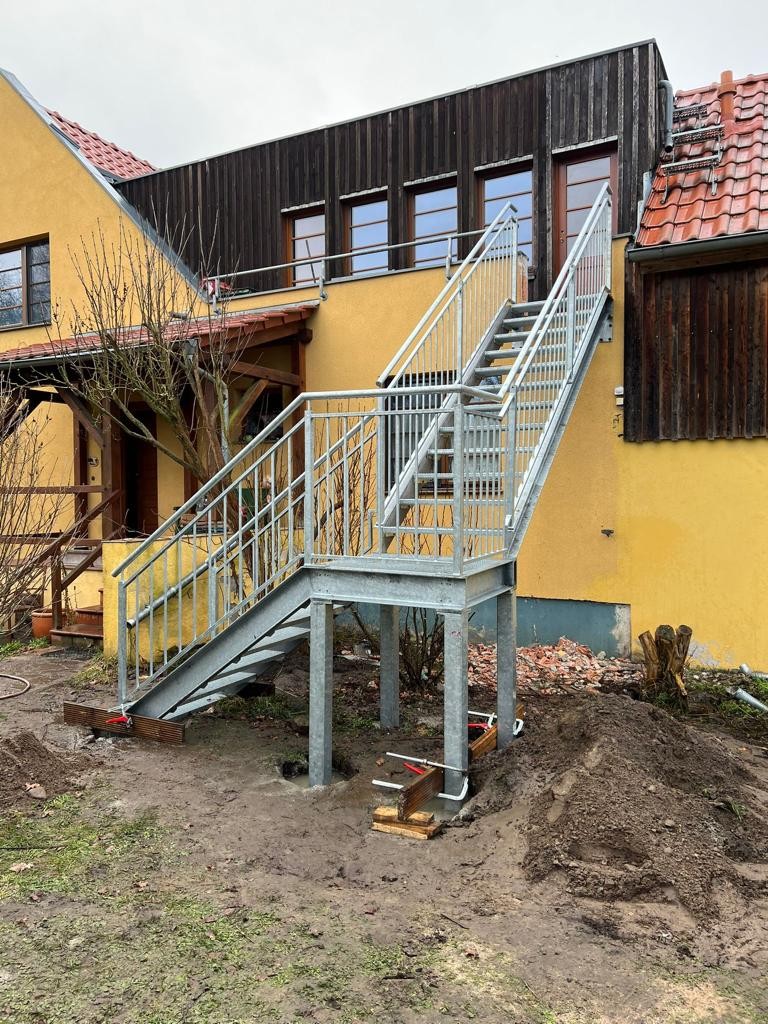 Metalltreppe im Garten eines gelben Hauses